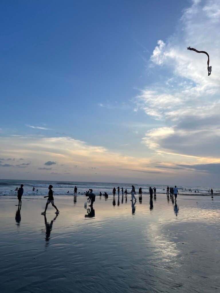 Plage de Canggu au coucher de soleil avec reflets des personnes sur l'eau